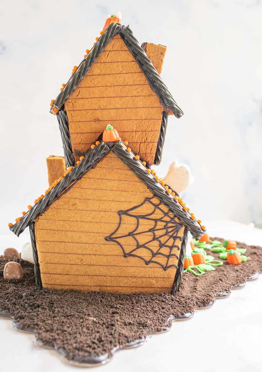 Back view of a Halloween gingerbread house with a spider web piped in icing across it