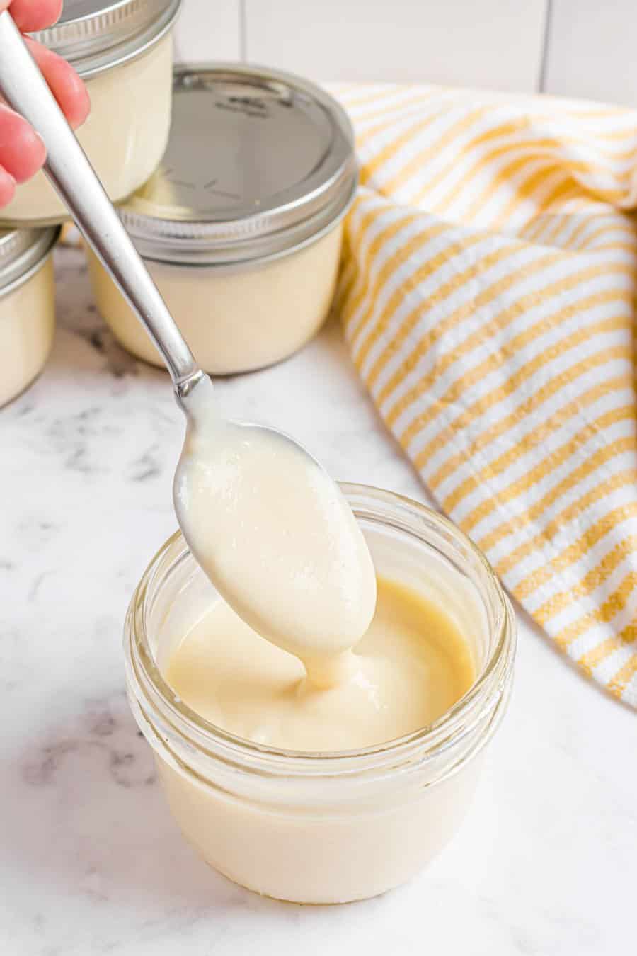 A spoonful of pudding dripping into a jar of pudding.