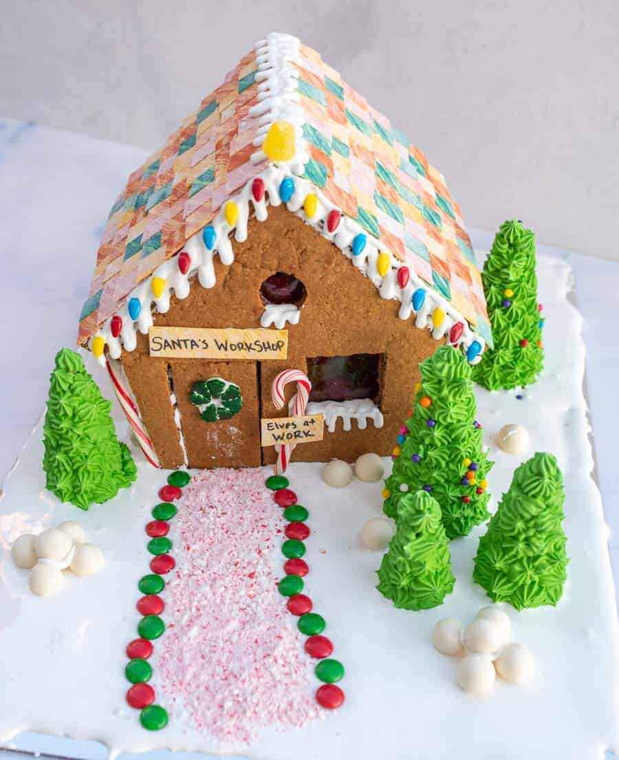 Finished "Santa's Workshop" gingerbread house with a chewing gum roof, and green icing trees.