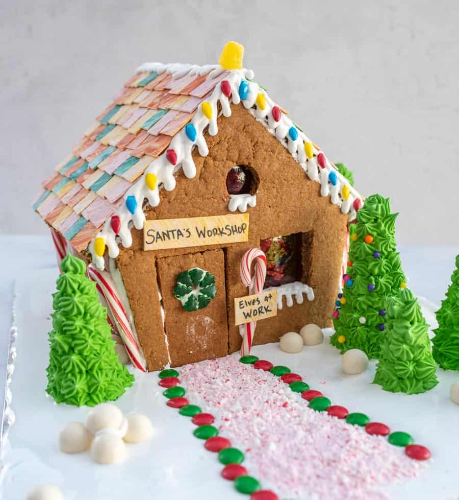 traditional gingerbread house beautifully decorated with a sign that says "santa's workshop"