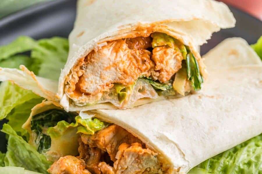 Two buffalo chicken wrap halves stacked on top of each other showing the chicken and lettuce inside.