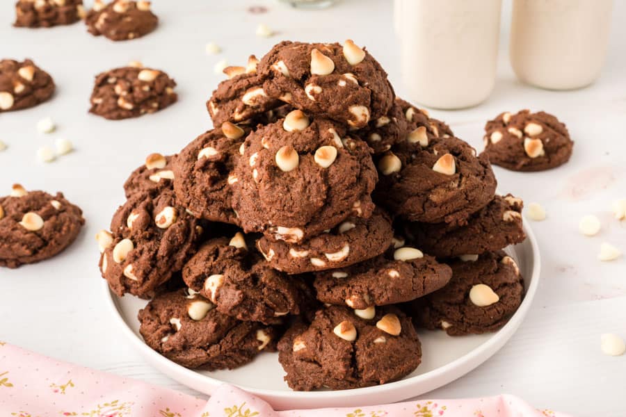 Chocolate cookies with white chips piled on a plate.