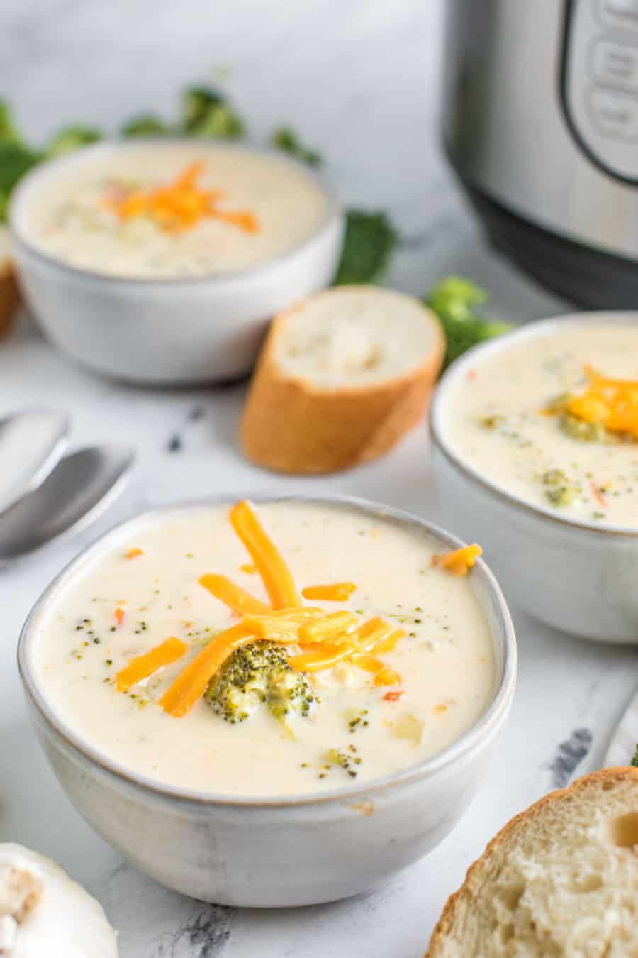 Up close of a bowl of broccoli and cheese soup topped with shredded cheddar cheese.