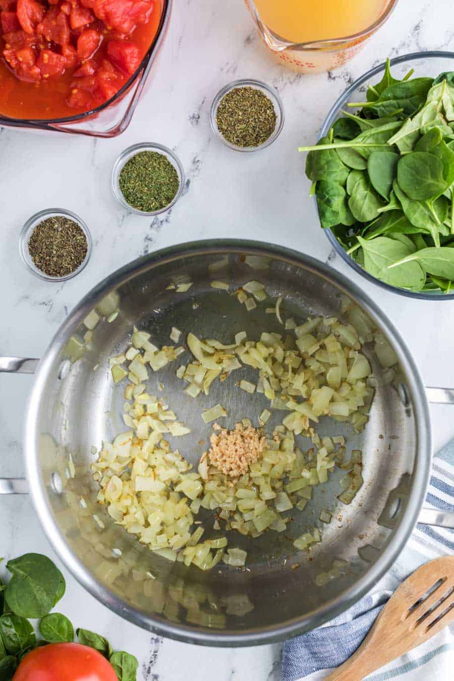 Top view of a pot with sautéed garlic and spices with onion cooked down.