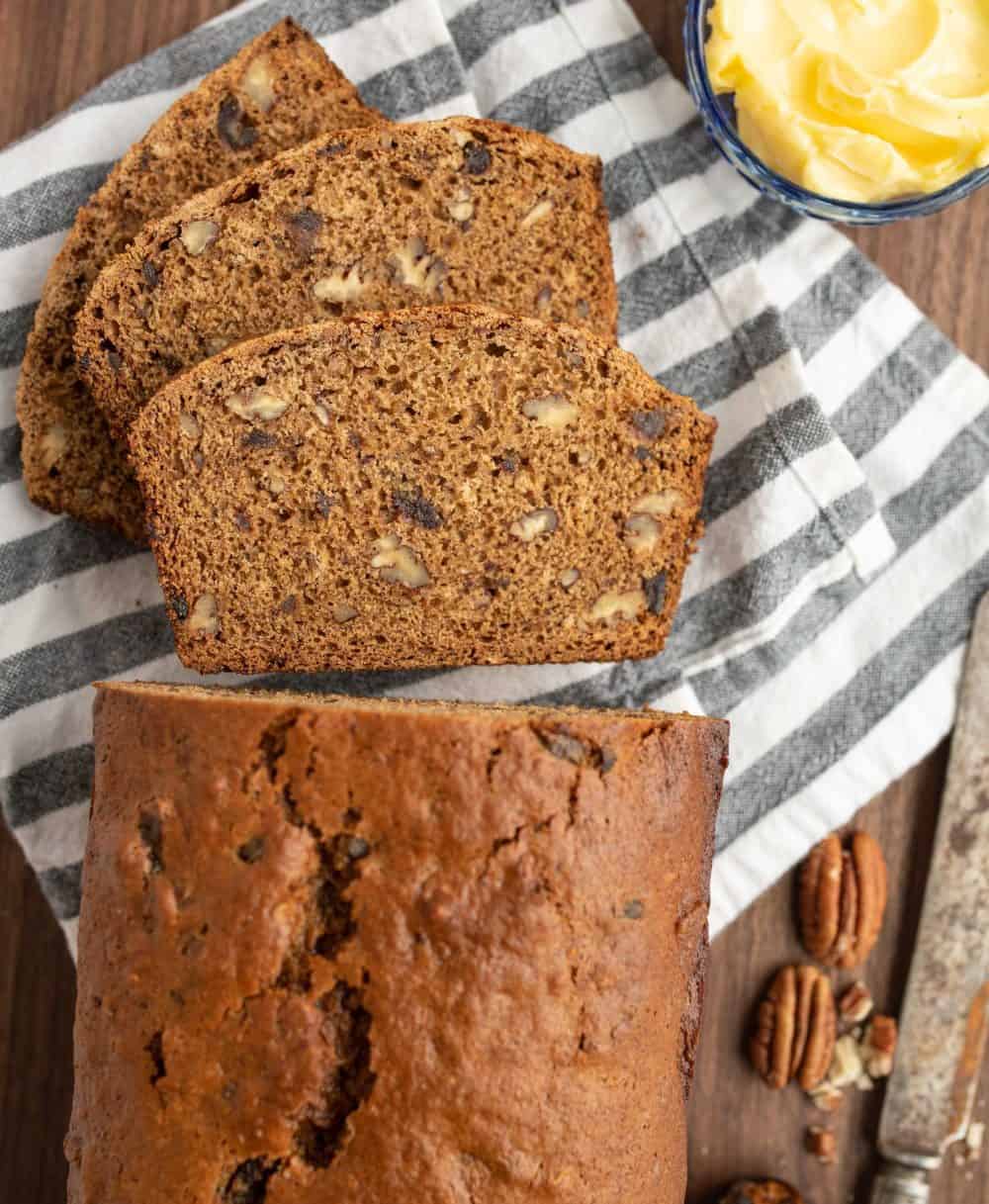 Top view of a loaf of date nut bread, half of it cut into slices.