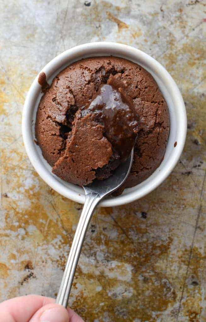 Top view of a chocolate molten lava cake with a spoon scooping out the gooey chocolate in the center.