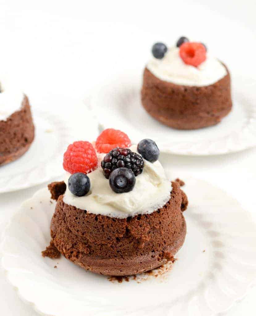 Chocolate molten lava cake on a plate with ice cream and berries on top.