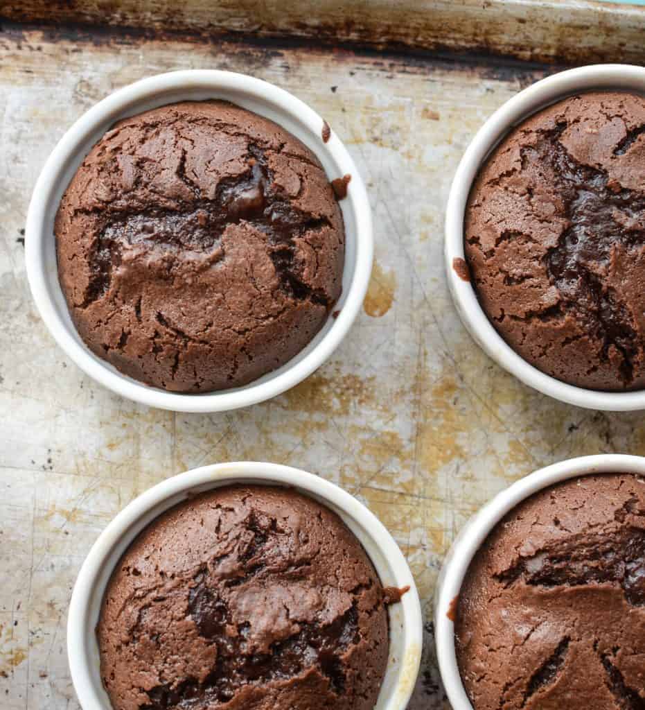 Top view of four chocolate molten lava cakes baked in their ramekins.