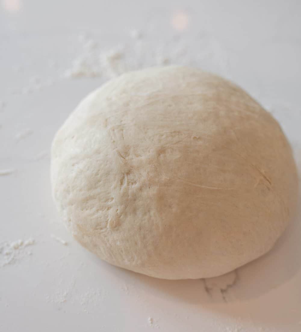 sourdough bread ball rolled onto a white table.