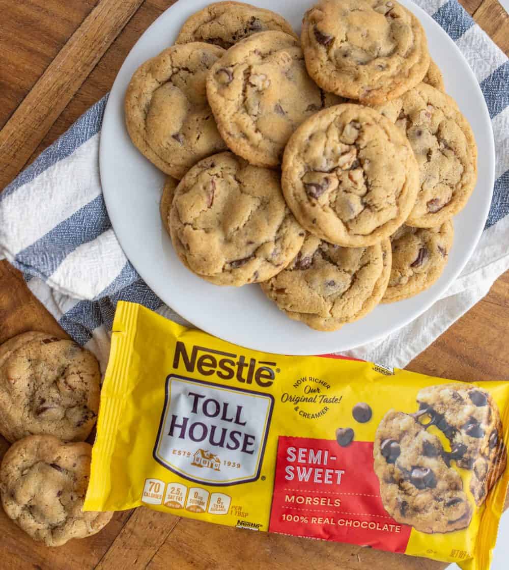 a plate stacked with chocolate chip cookies next to a bag of semi sweet chocolate morsels made from the original toll house cookie recipe.