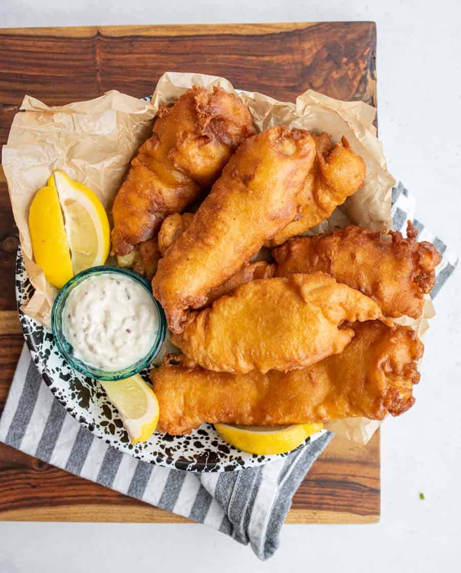 top view - crispy golden deep fried and beer battered fish with tartar sauce and lemons.
