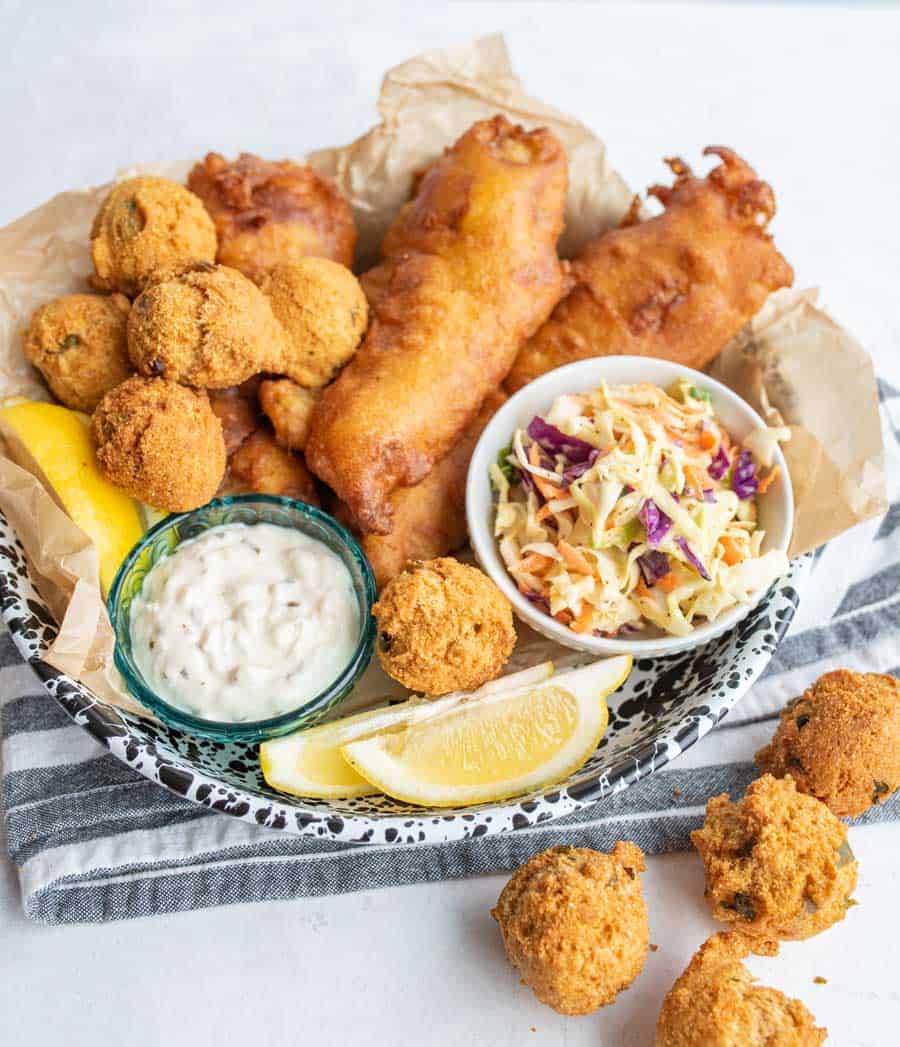crispy deep fried and beer battered fish and hush puppies with tartan and lemons and coleslaw.