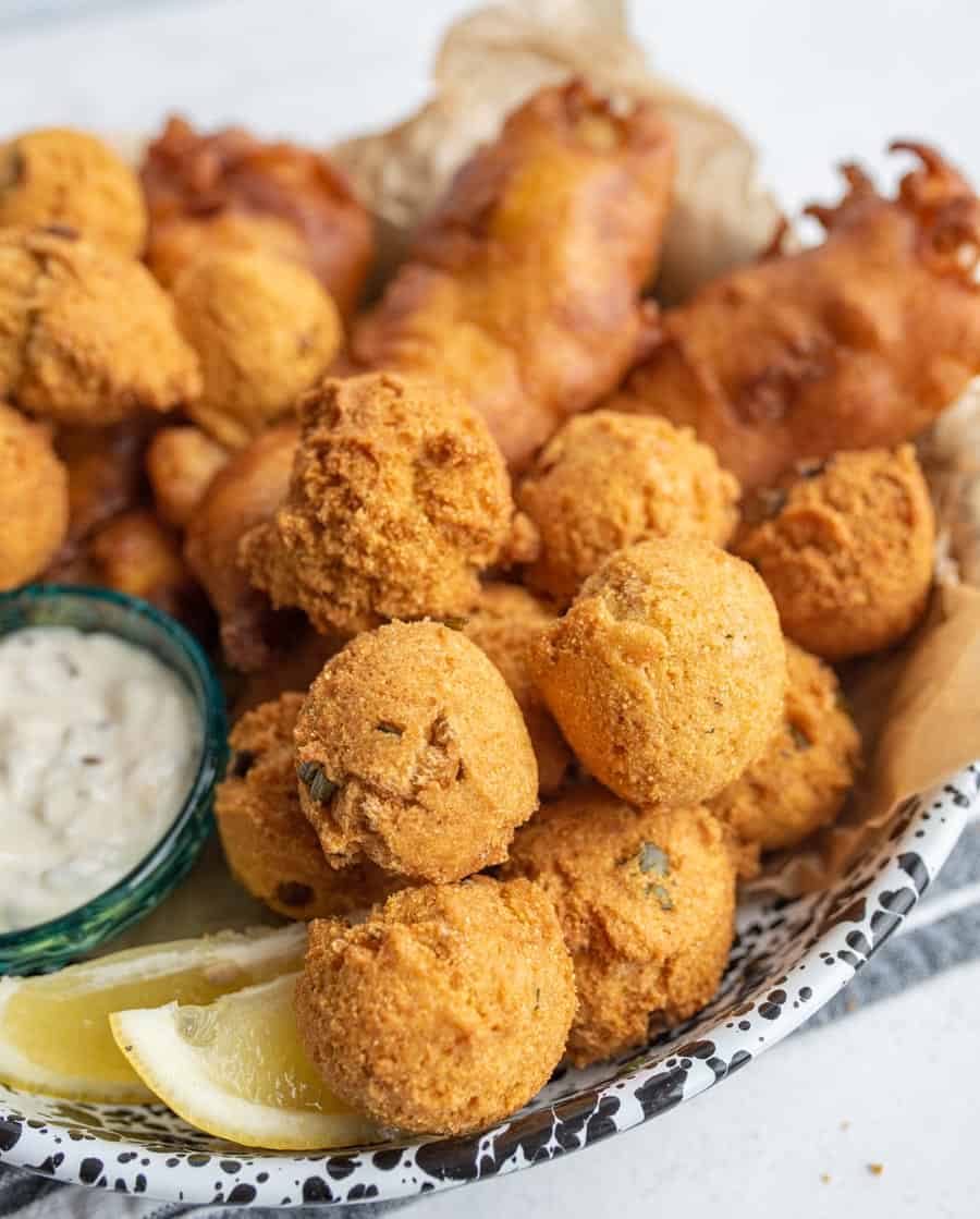 close up of the hush puppies with crispy fried beer batter fish in the background.