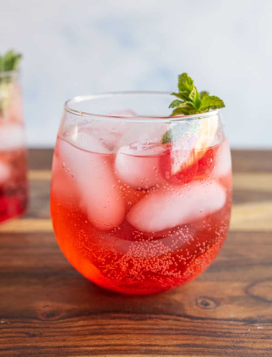 round tumbler of a red "Shirley-Temple" drink with ice cherries and garnish.