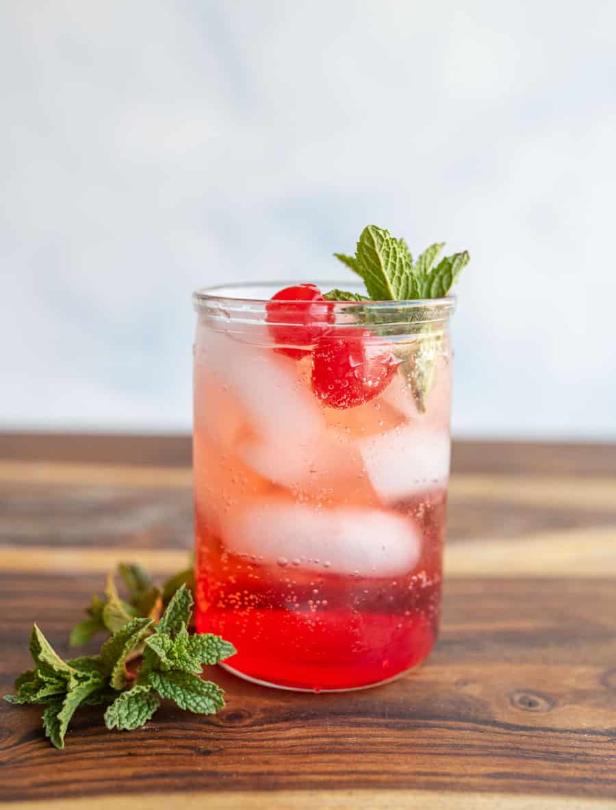 tumbler of a red "Shirley-Temple" drink with ice cherries and garnish..