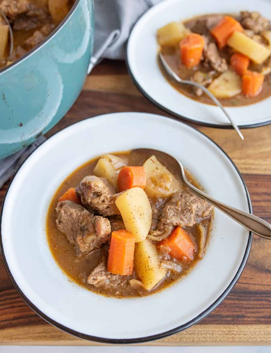 two bowls of hearty and traditional beef stew with a spoon.