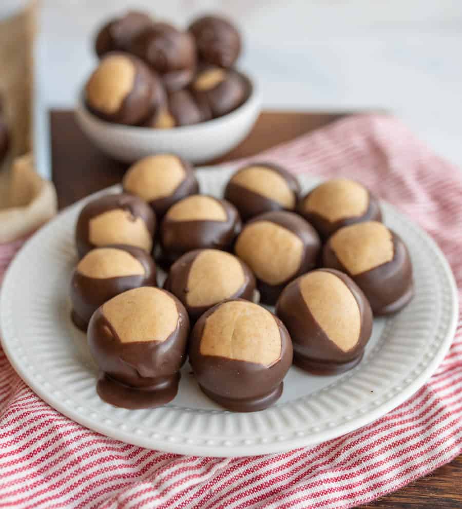 round truffle like chocolates piled on a pate and in a bowl with what looks like a lighter color to the shell of each.