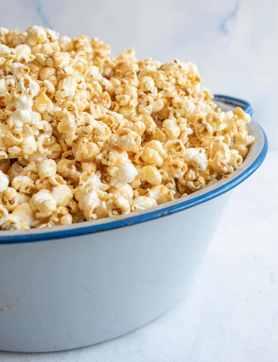 side view of soft caramel popcorn on a big white and blue bowl.