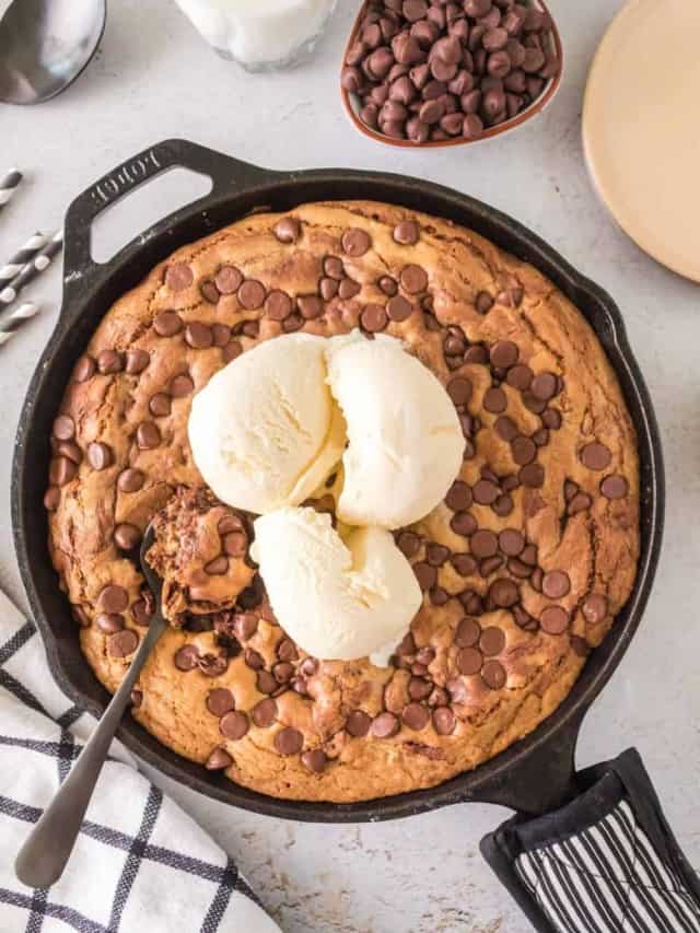 chocolate chip cookie baked in cast iron pan with scoop of vanilla ice cream on top.