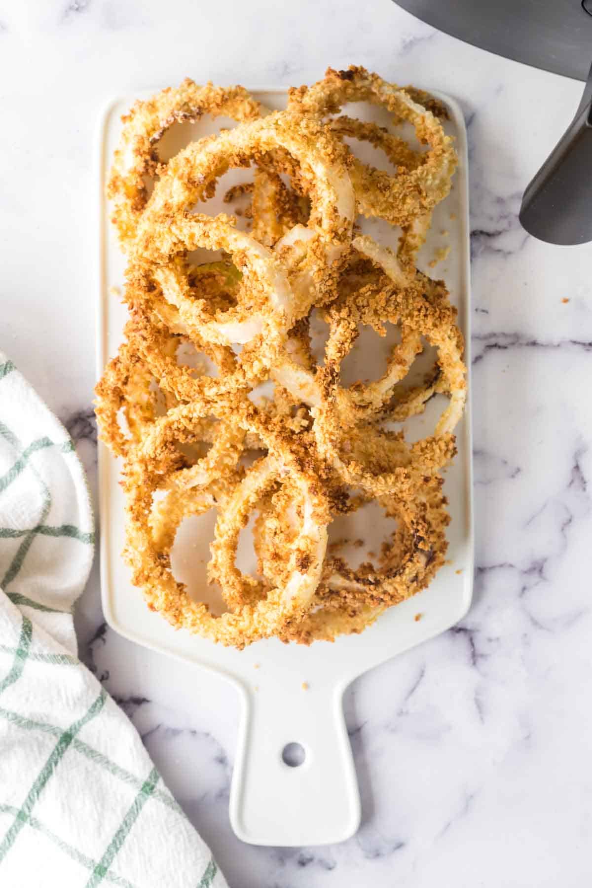 a plate of crispy golden air fryer onion rings on a dish.