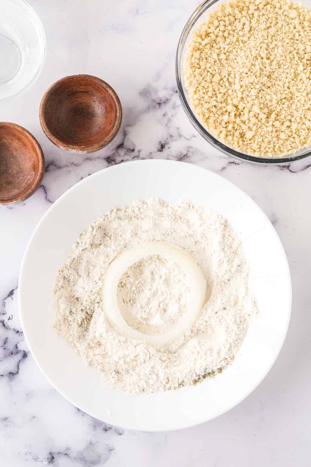 raw onion being dusted in flour and breaded.