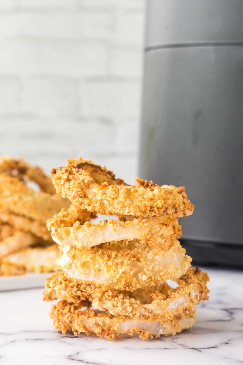 golden brown onion rings in a stack on the counter.