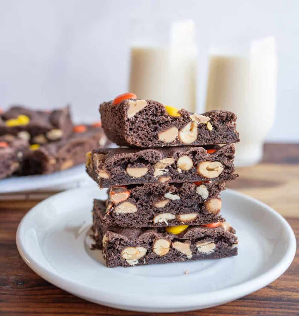 Stack of cake bars with glasses of milk in the background.