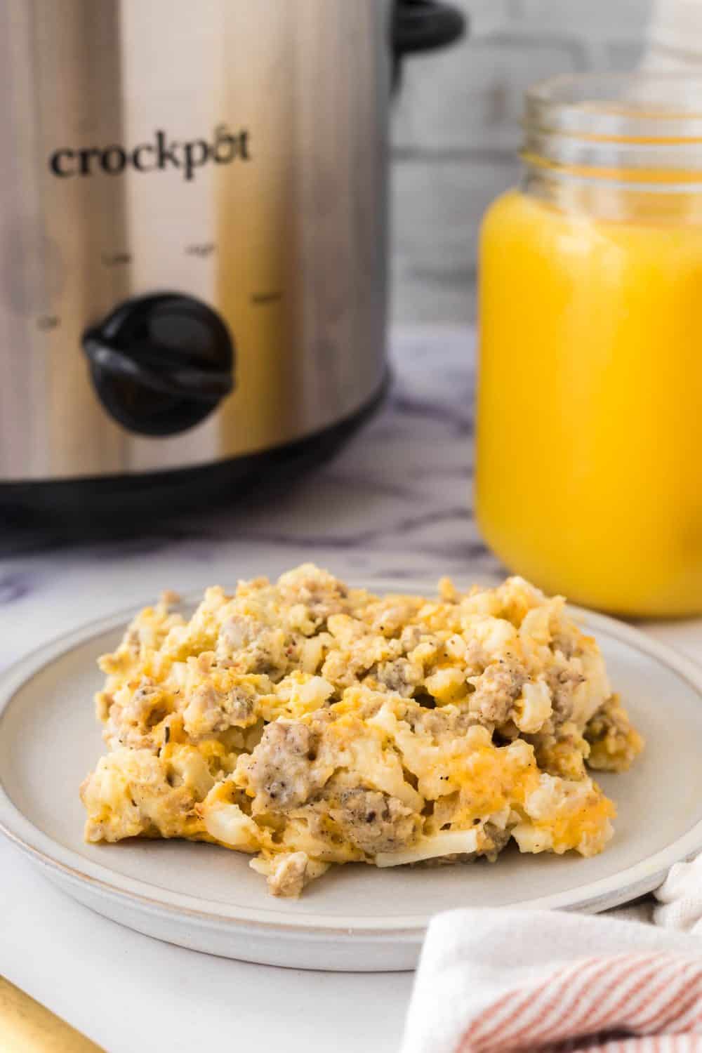 Crockpot breakfast casserole with orange juice in the background.