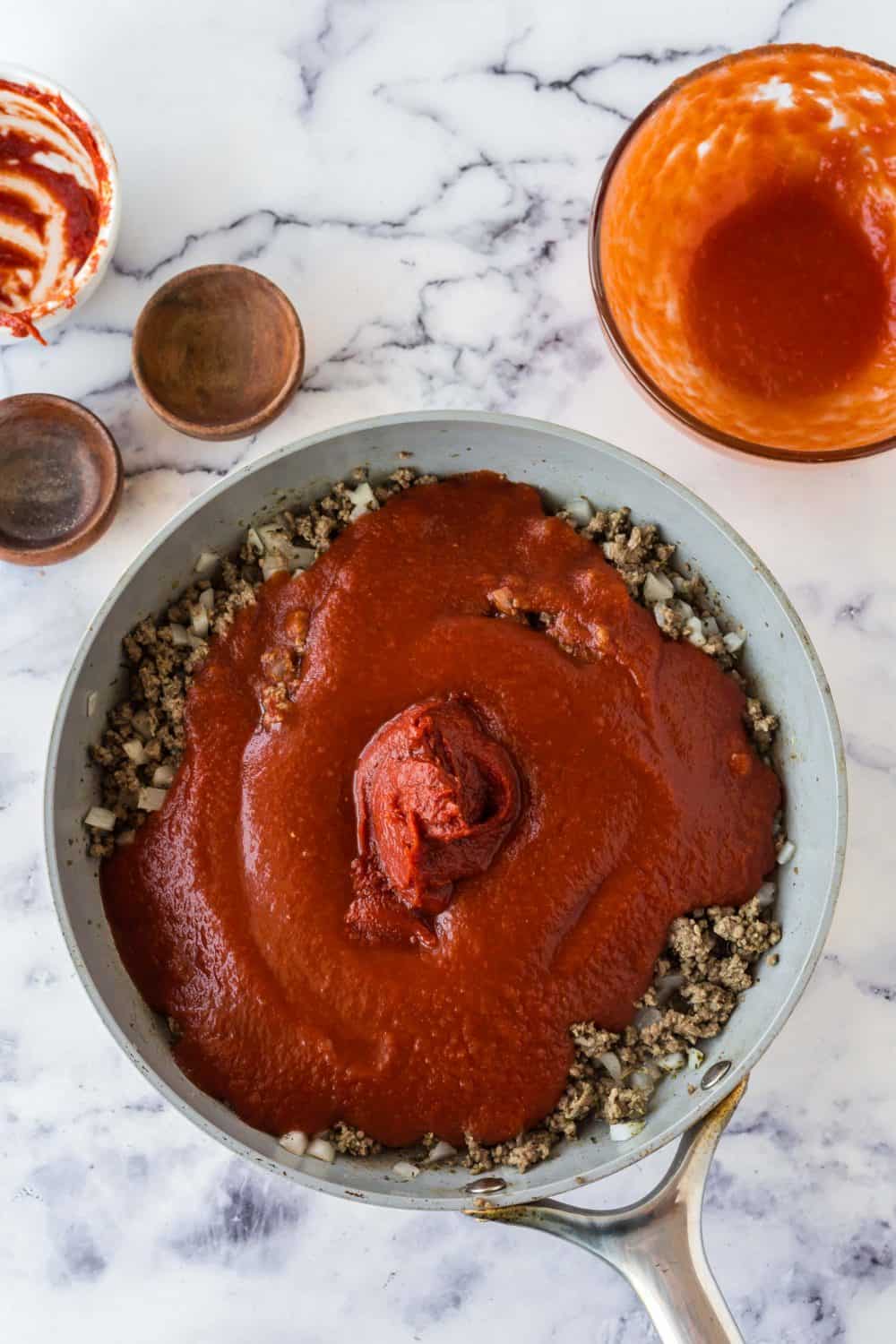 ingredients for meat sauce added one by one and a cooking in a pot