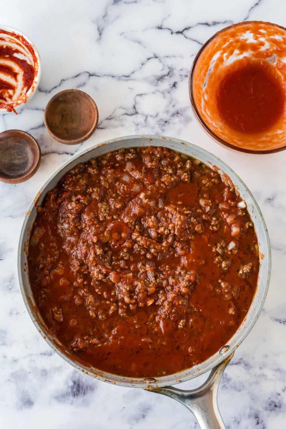 ingredients for meat sauce added one by one and a cooking in a pot