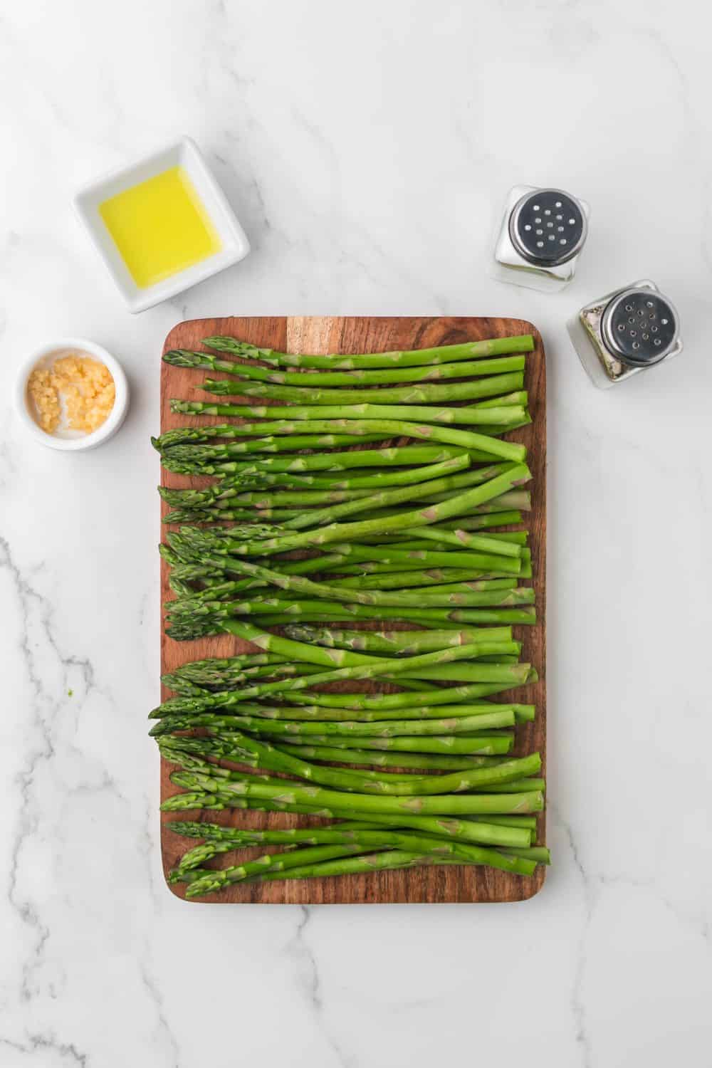 wooden cutting board of ripe green asparagus.