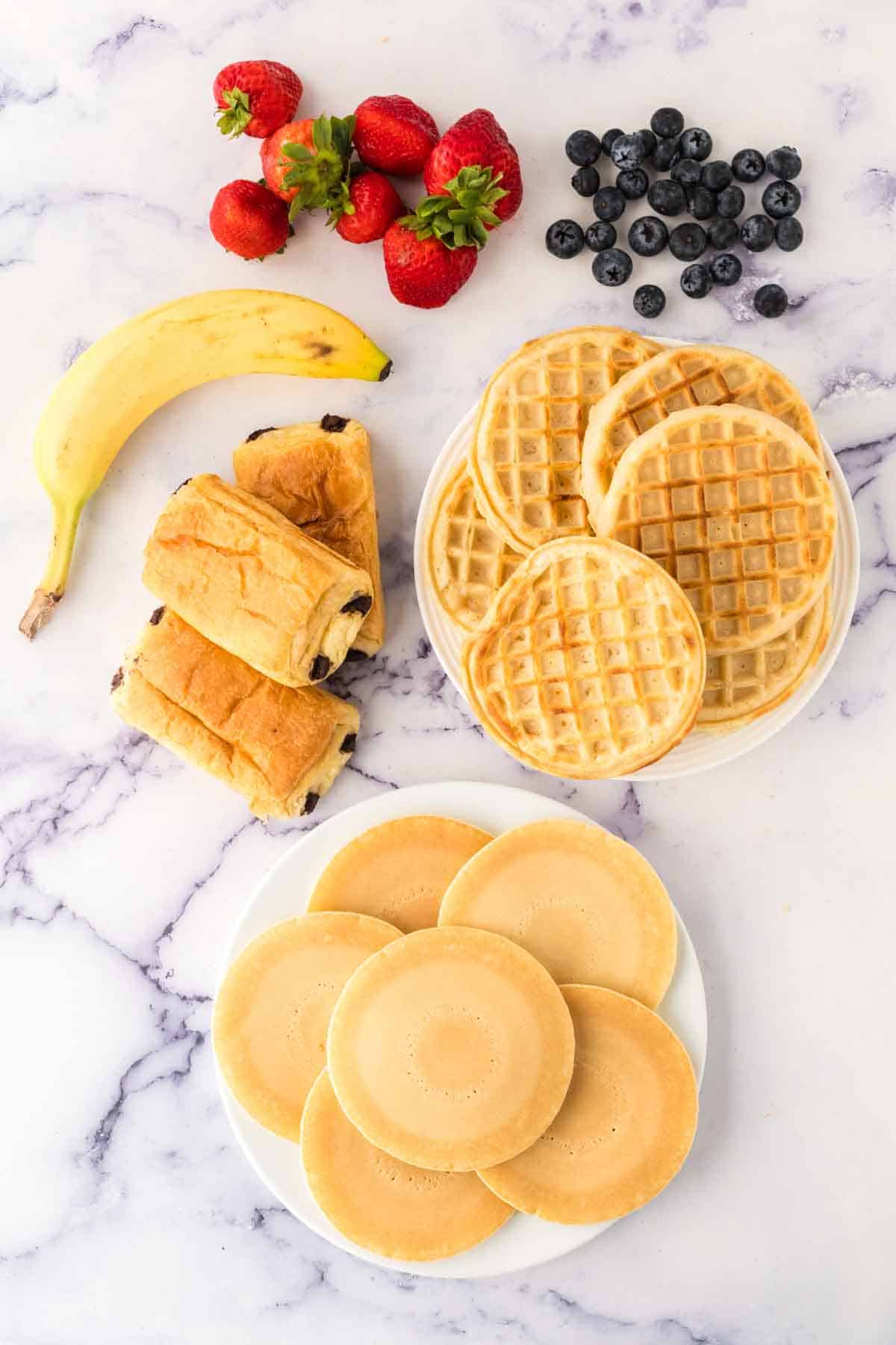 Elements for a breakfast charcuterie including waffles and pancakes.