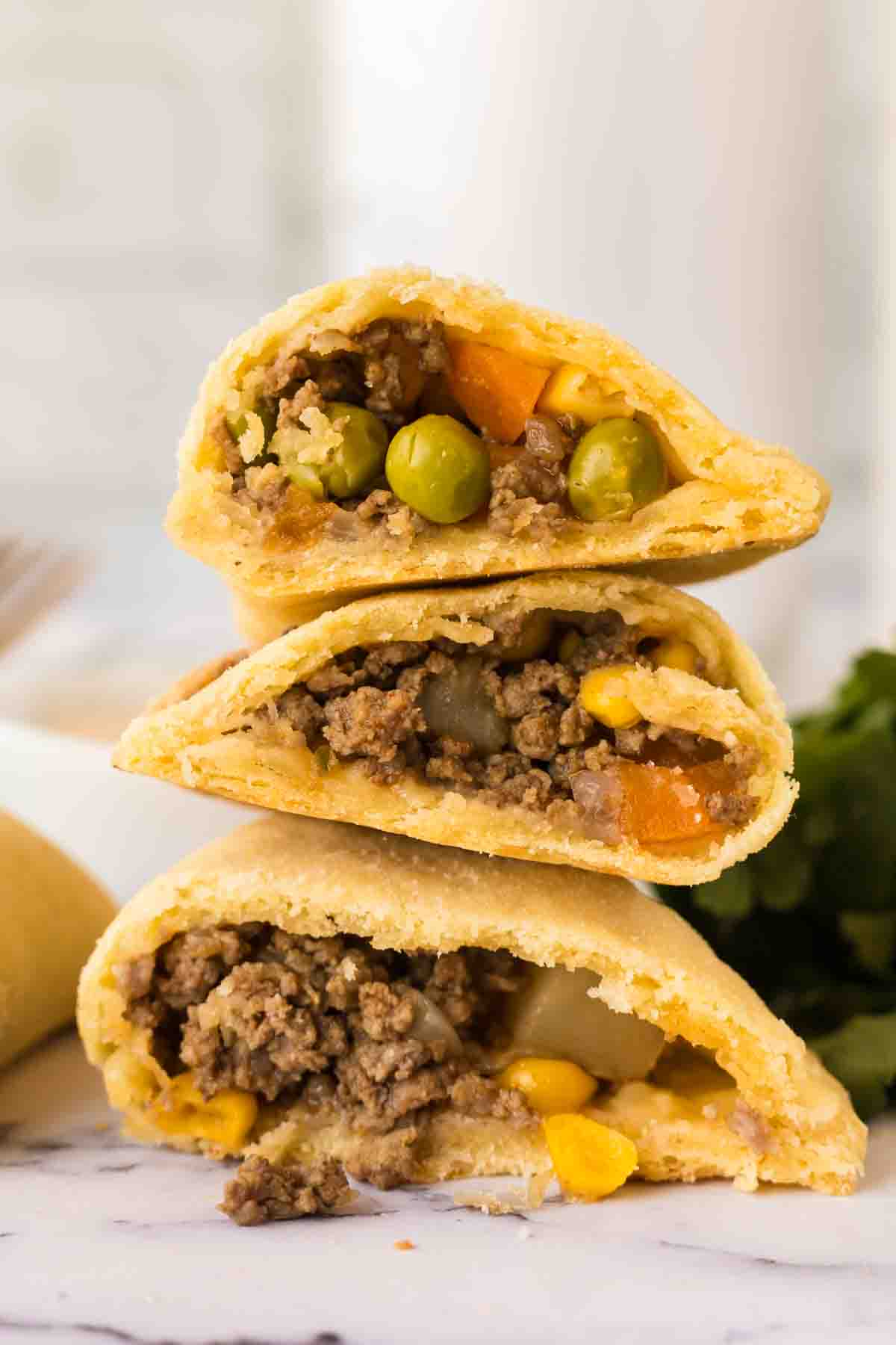 a plate stacked with three halved centers of empanadas