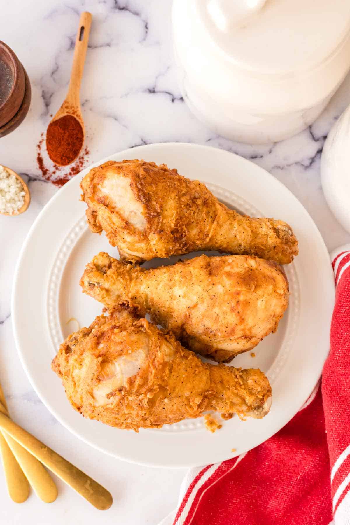 top view of a white plate with three Louisiana fried chicken legs.