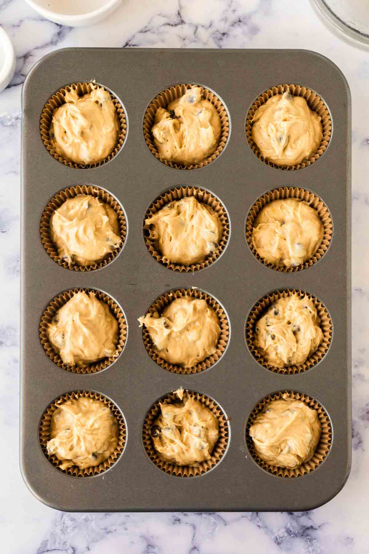 muffin tins with banana chocolate chip muffin batter