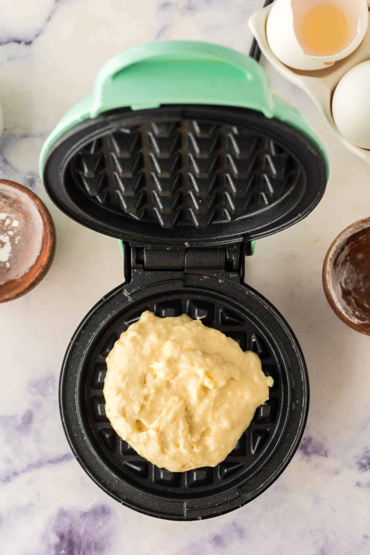 top view of a waffle iron and the batter going in.