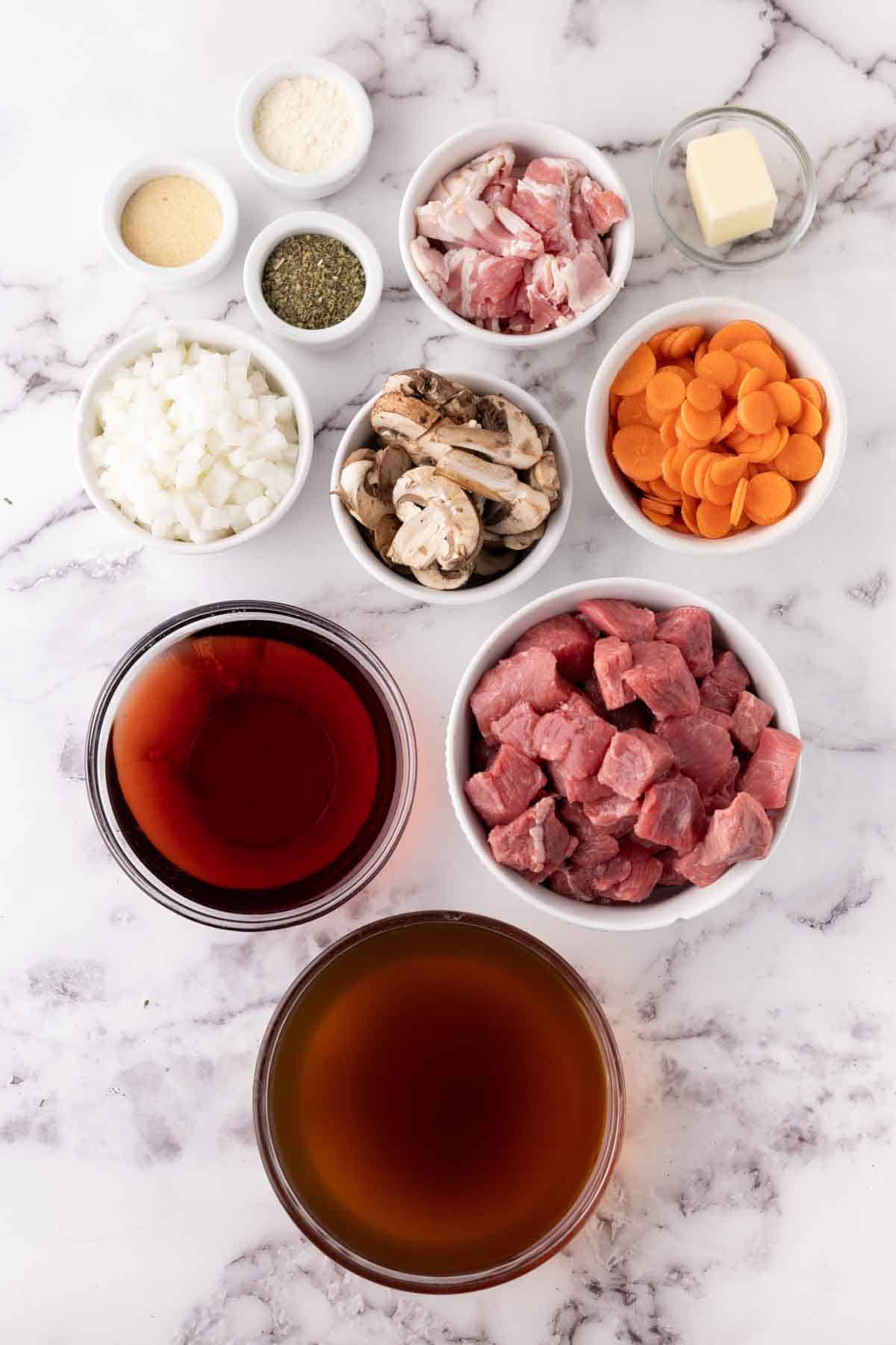 portion bowls each with raw ingredient to make Beef Bourguignon Recipe.