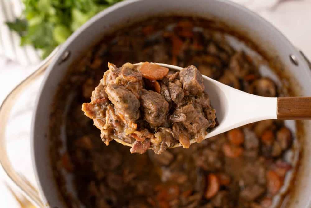 white spoon over a big pot of Beef Bourguignon Recipe.