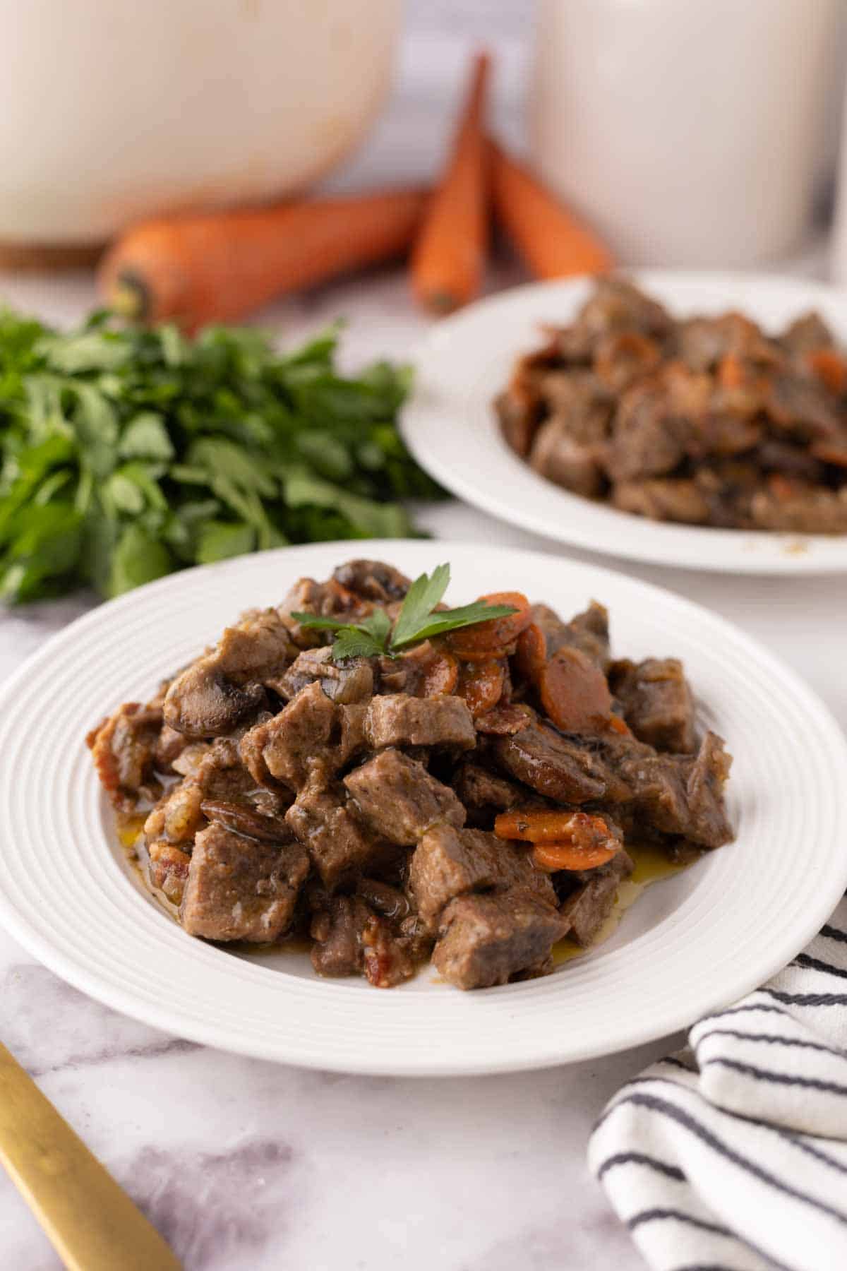 Beef Bourguignon Recipe served on a white plate with golden forks.