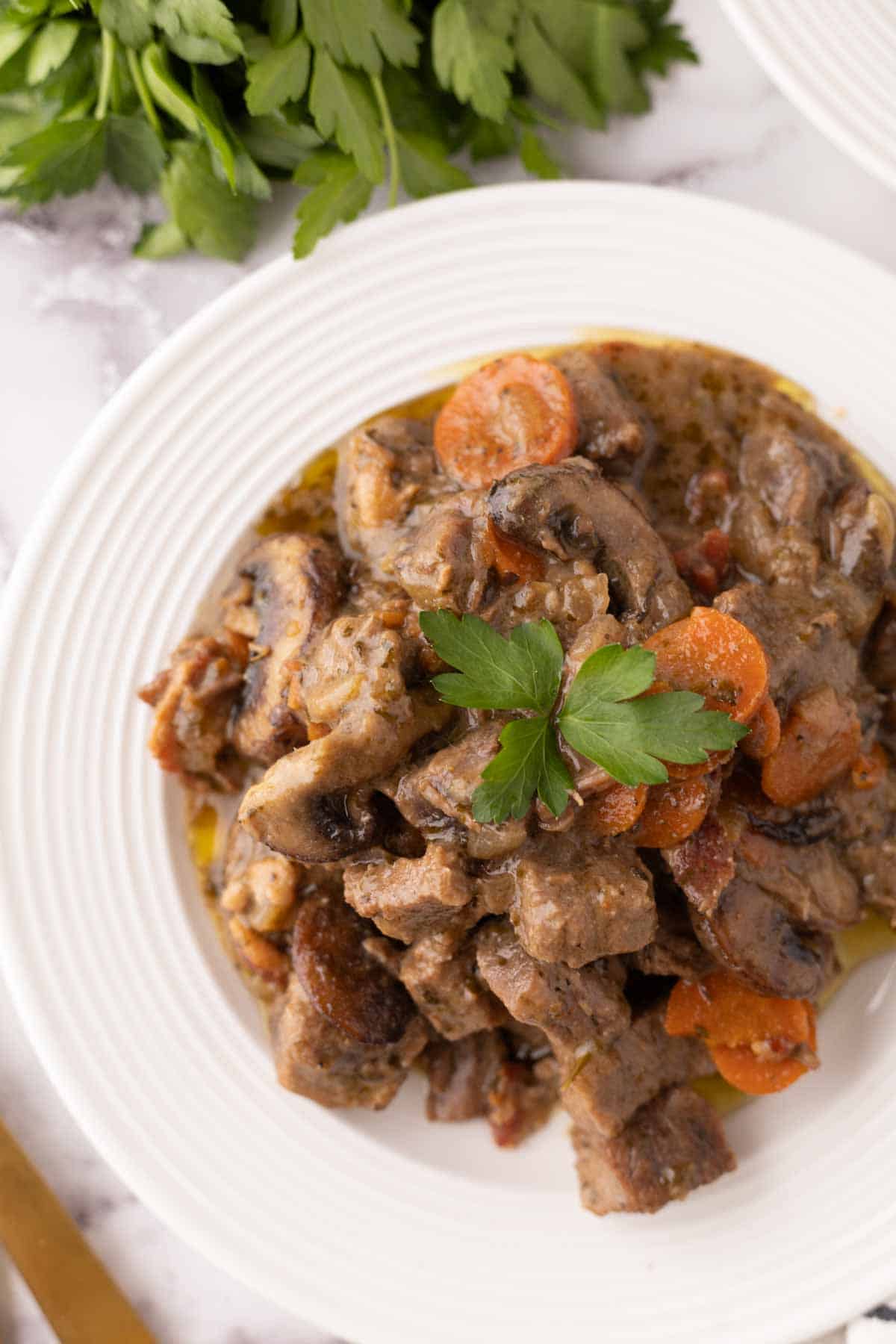 Beef Bourguignon Recipe served on a white plate with golden forks.