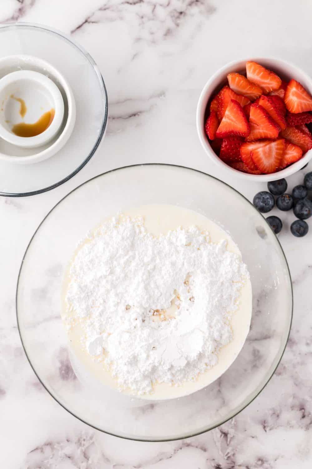 clear mixing bowl with the progress of berries and cream.