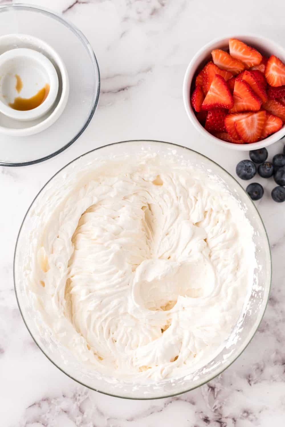 clear mixing bowl with the progress of berries and cream.