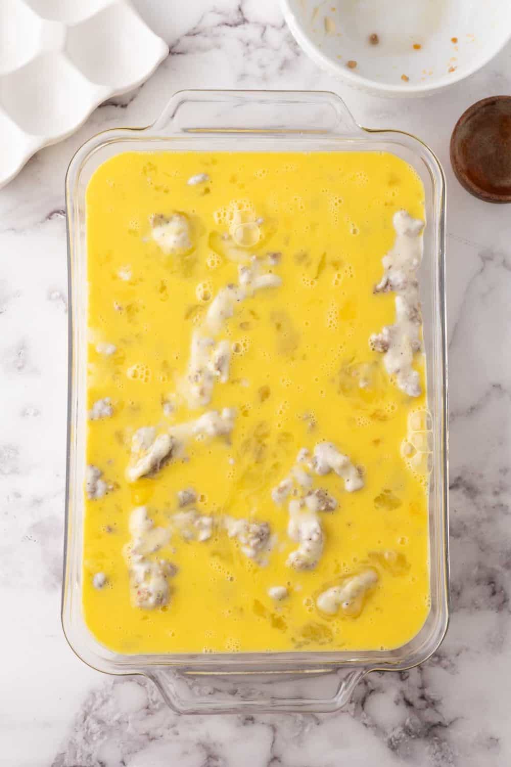 biscuits and gravy casserole recipe with uncooked eggs poured in.