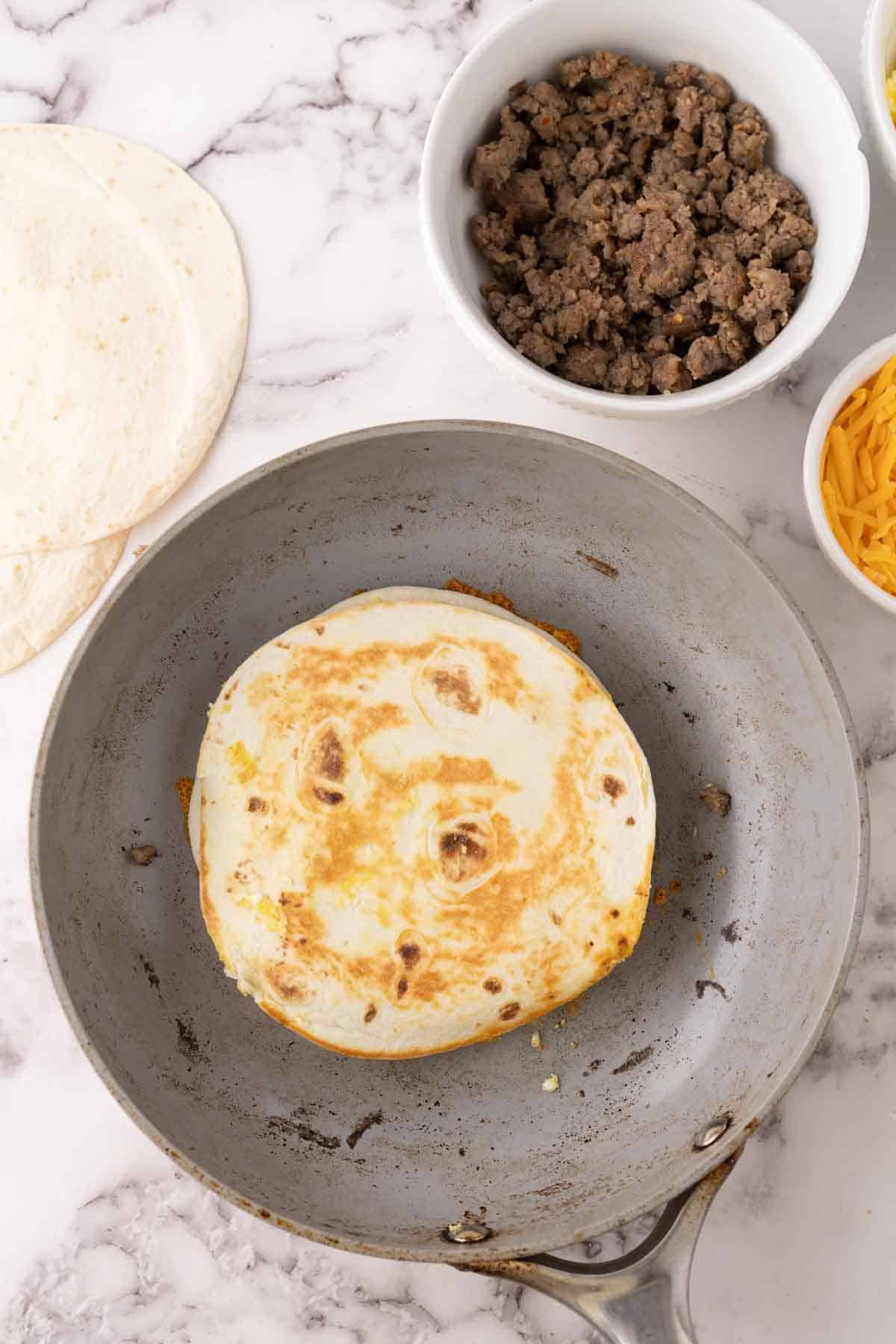 browned flour tortilla with breakfast quesadilla recipe in progress.