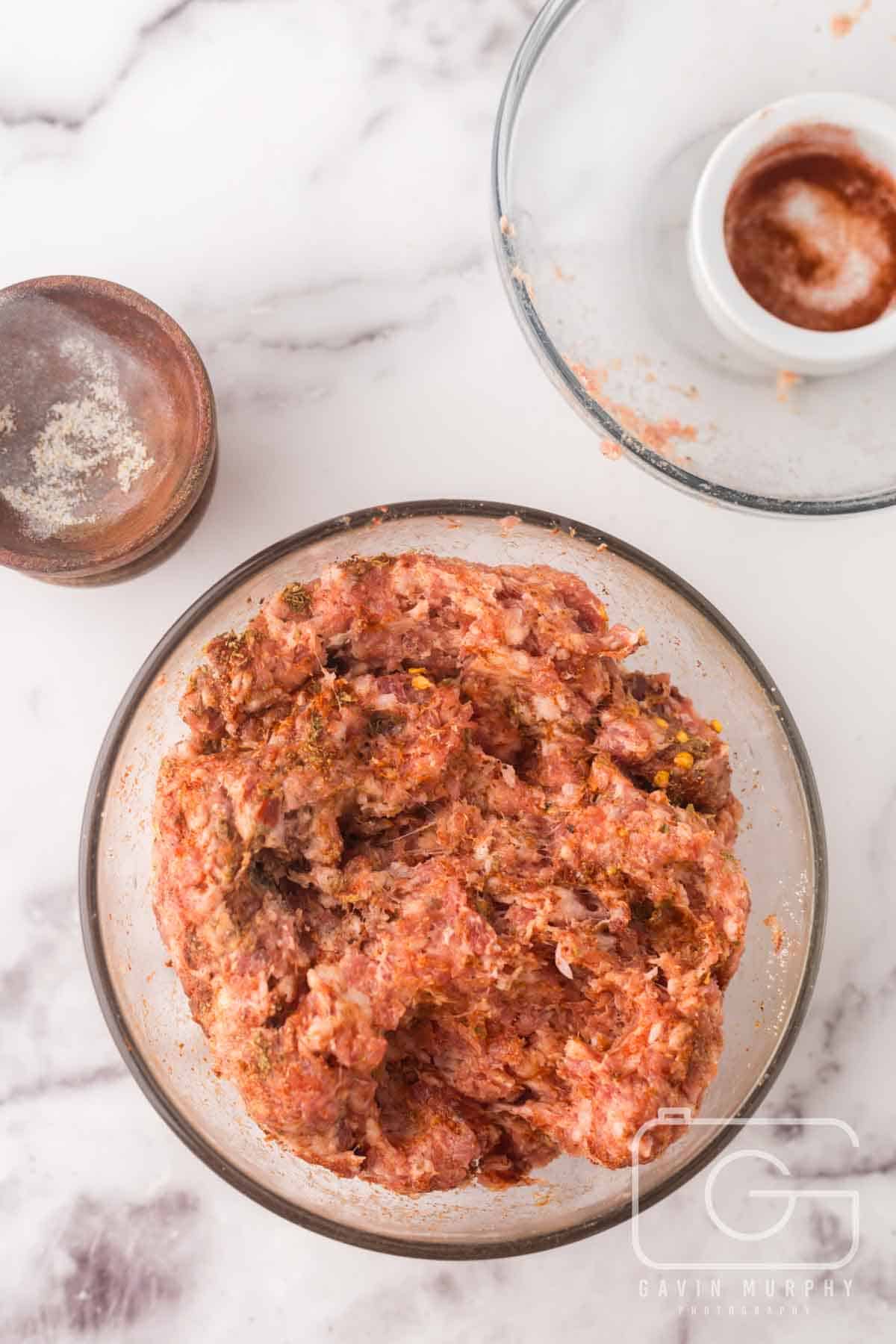 clear mixing bowl with sausage and seasonings.