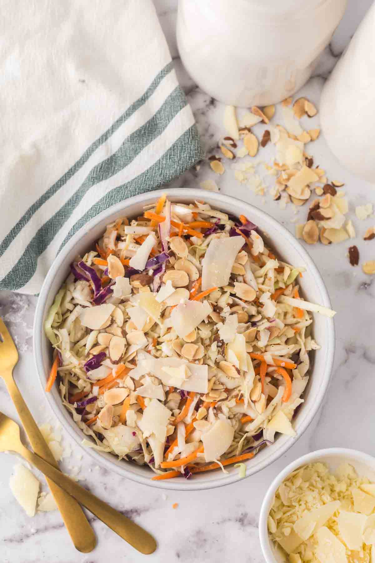 cabbage salad recipe in a white bowl with golden forks to the side.
