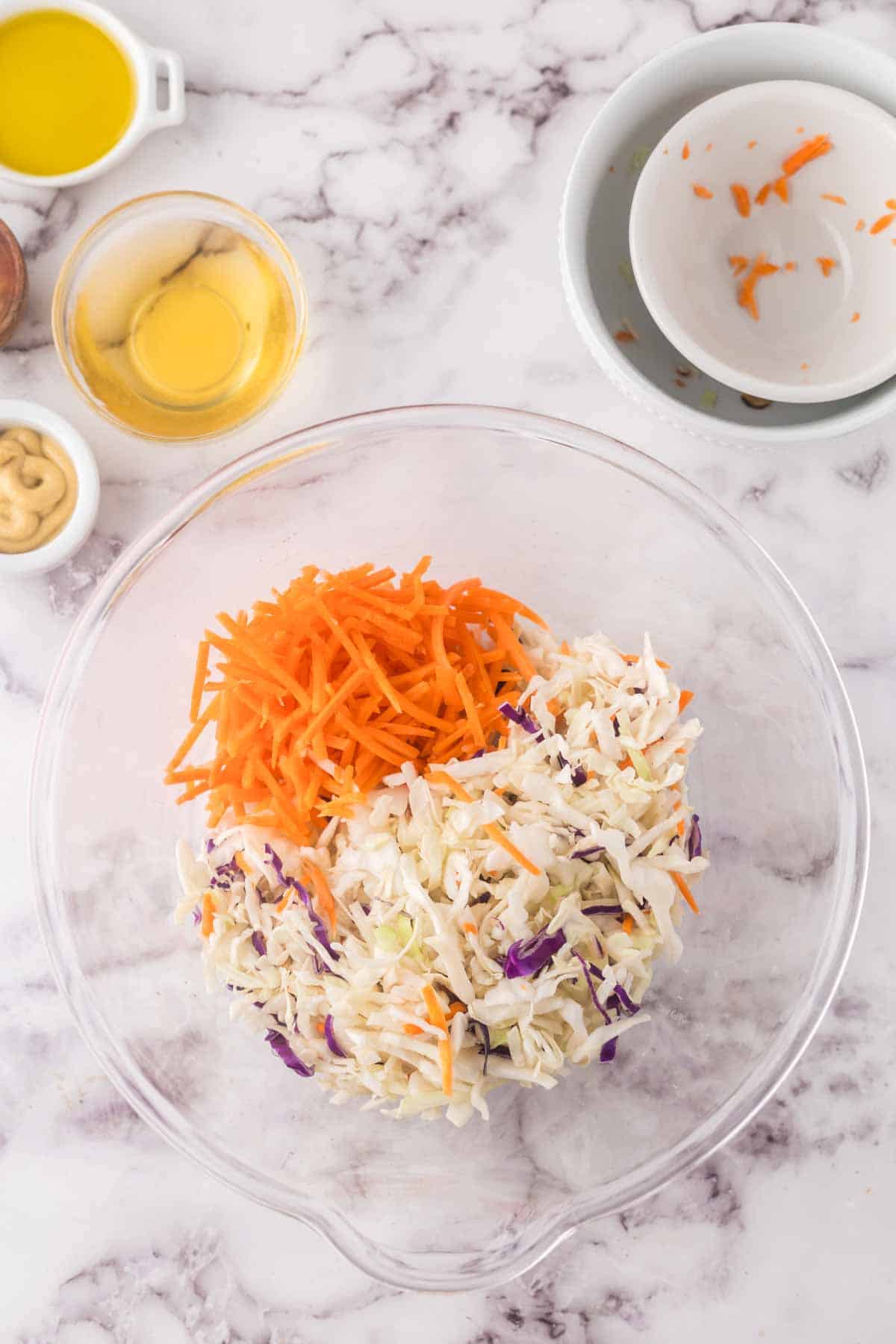 clear mixing bowl with the progress of making cabbage salad.