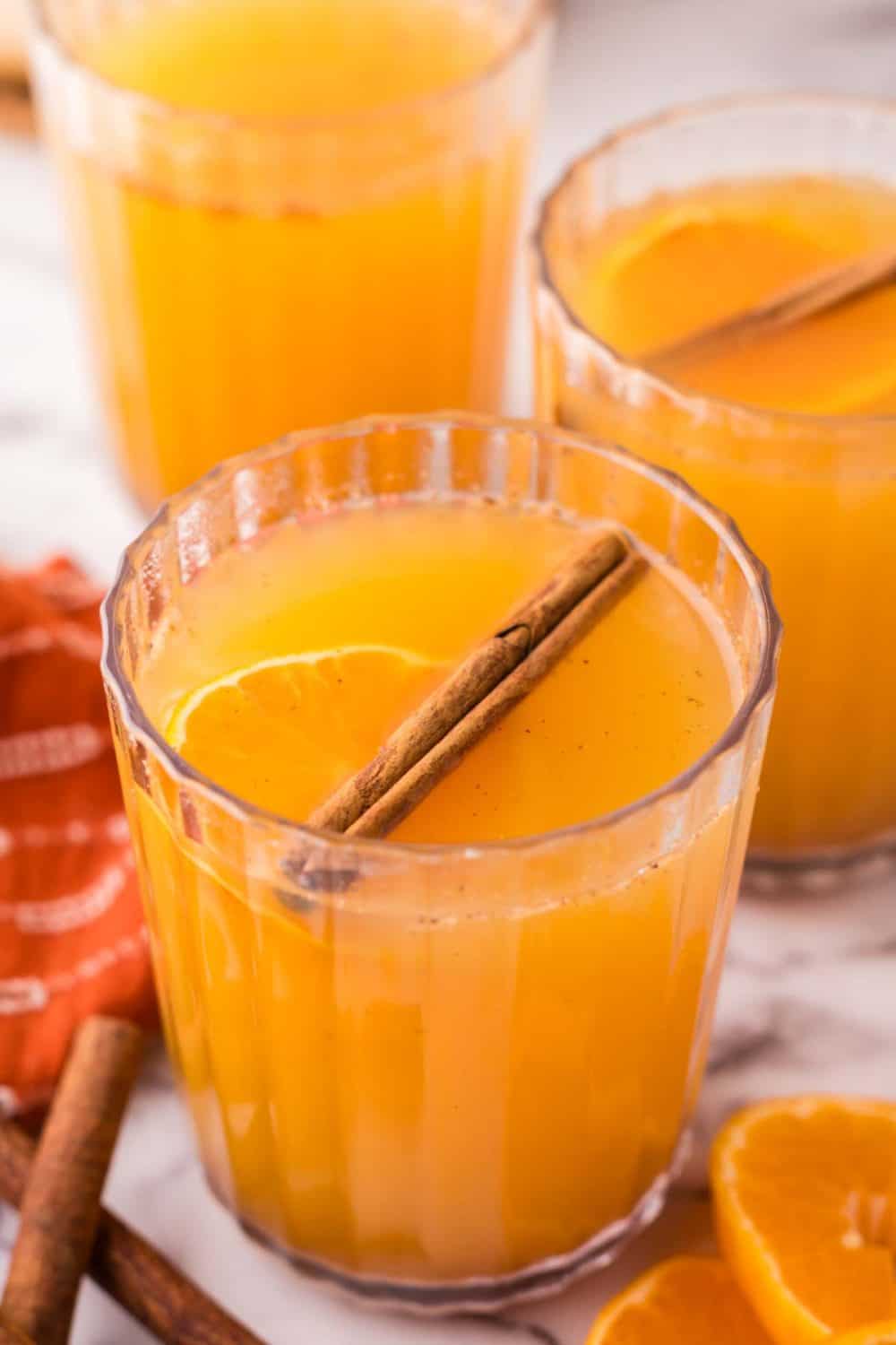 Glasses of wassail with cinnamon sticks.