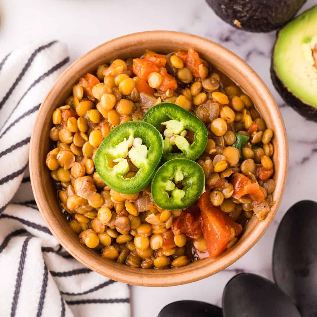 bowl of lentil chili with fresh sliced jalapeño on top.