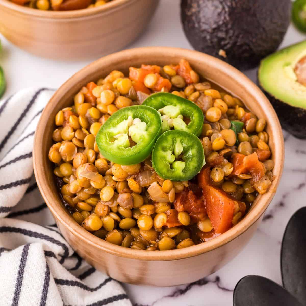 bowl of lentil chili with fresh sliced jalapeño on top.